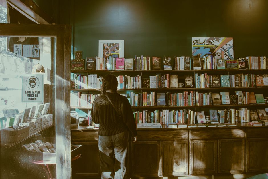 A bustling indoor book sale with numerous books and diverse people browsing.