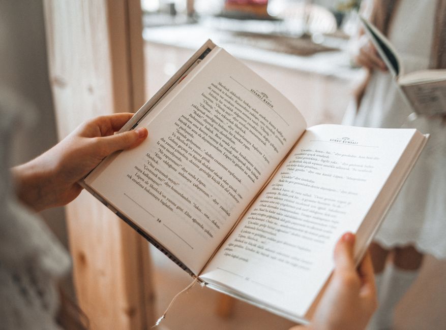 A gloved hand holds a weathered copy of The Catcher in the Rye outdoors.